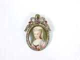 une petite image représentant une femme en robe, fixée sur une broche