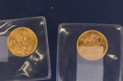 deux pièces d'or dans des étuis en plastique posées sur un fond bleu