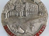 une pièce d'argent sur laquelle sont représentés une maison et un bateau