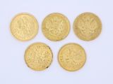 quatre pièces d'or superposées sur une surface blanche
