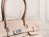 a beige leather handbag sitting on top of a wooden table