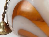 a white and orange vase with a bell on a table