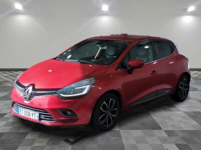 une voiture rouge est garée dans une pièce au sol en damier