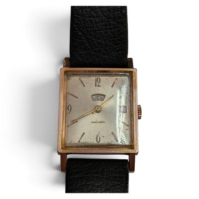 une vieille montre avec un bracelet en cuir noir posée sur un fond blanc