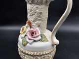 a white vase with a pink rose on top of it