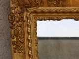 a gold framed mirror hanging on a wall next to a wall
