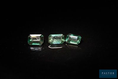 a pair of emeralds on a black surface