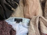 a pile of clothes and a handbag on a bed