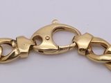 a close up of a gold chain bracelet on a white surface