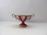 a red and gold bowl on a white table