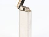 silver lighter on a white surface with a reflection on the ground