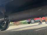 a person standing under a car on the side of the road