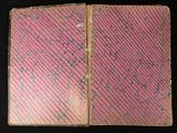 an old book with a pink cover on a black background