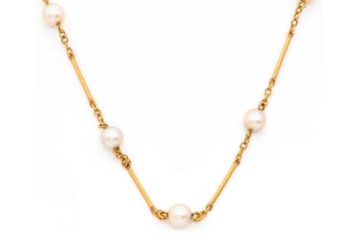 un collier en or avec des perles et une chaîne sur fond blanc
