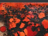 a close up of a red and black painting on a black surface