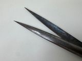 pair of metal scissors on a white surface with a white background