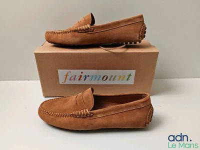 mocassins beiges avec une boîte posée sur un fond blanc