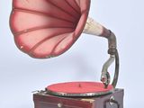 an old gramphone with a red horn on a wooden stand