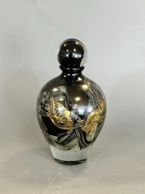 a black and gold vase sitting on a white surface
