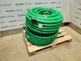 a green hose sitting on a pallet in front of a wall