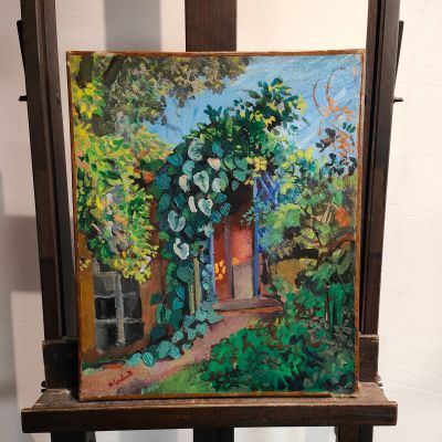une peinture à l'huile représentant une maison dans un jardin, posée sur un chevalet