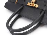 a close up of a black purse on a white surface