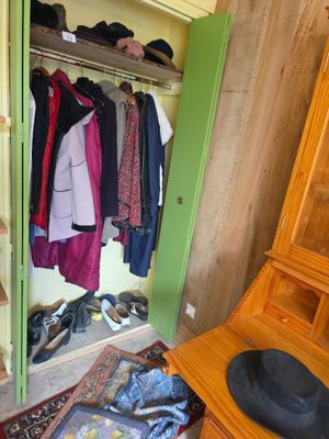un placard rempli de vêtements et un chapeau par terre