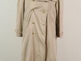 un trench-coat posé sur un pied de mannequin dans une pièce blanche