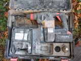 une mallette à outils contenant des outils, posée par terre