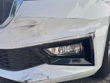 a close up of the front of a white car with a dent on it