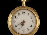 a close up of a gold pocket watch on a black background