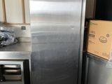 un réfrigérateur argenté au milieu d'une cuisine, avec des cartons sur le plan de travail