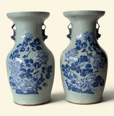 une paire de vases bleus et blancs ornés de fleurs, posés sur un fond blanc