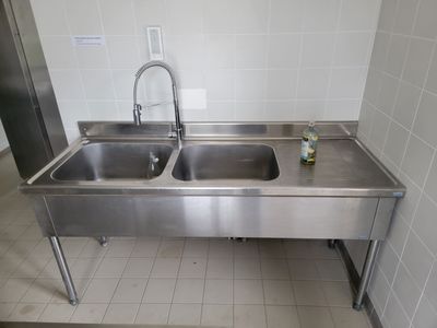 un lavabo en acier inoxydable et un robinet en acier inoxydable dans des toilettes publiques