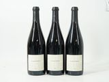 trois bouteilles de vin sont alignées sur une surface blanche