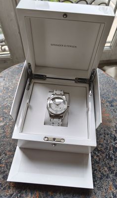 une boîte ouverte contenant une montre, posée sur une table