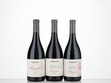 three bottles of red wine are lined up on a table