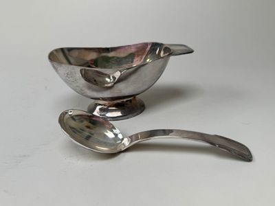 a silver spoon and a silver bowl on a white table
