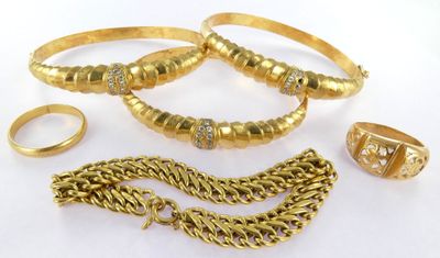 several gold rings, bracelets, and a ring on a white surface