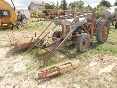 un tracteur garé dans l'herbe, à côté d'autres machines agricoles