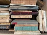 pile of old books sitting on top of each other in a cardboard box