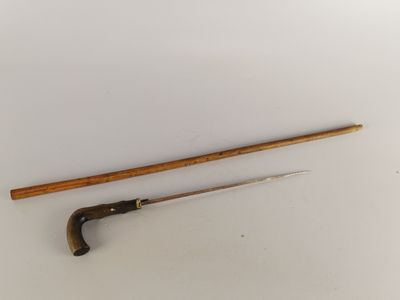 une vieille canne en bois et une canne posées sur une surface blanche