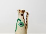 un vase blanc orné d'un visage vert