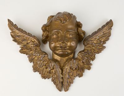 an image of a gold angel head with wings on a white wall