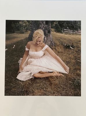 a picture of a woman sitting on the ground in a white dress