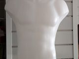 a white mannequin sitting on a glass shelf in a room