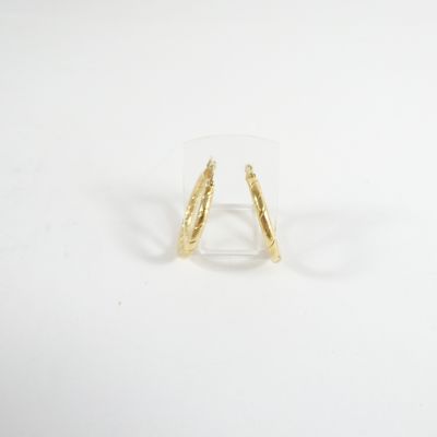 gros plan d'une paire de boucles d'oreilles en or sur une surface blanche