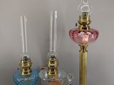 three different colored glass candlesticks on a table