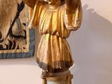 a statue of a child on a pedestal in front of a painting
