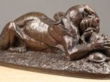 statue of a lion laying down on a rock with a bird in its mouth